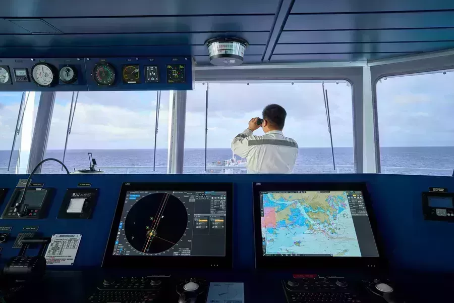 The bridge of the ship with ECDIS screens and mariner onboard looking out to sea